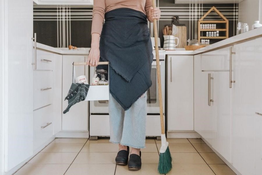 a woman standing in a kitchen holding a broom